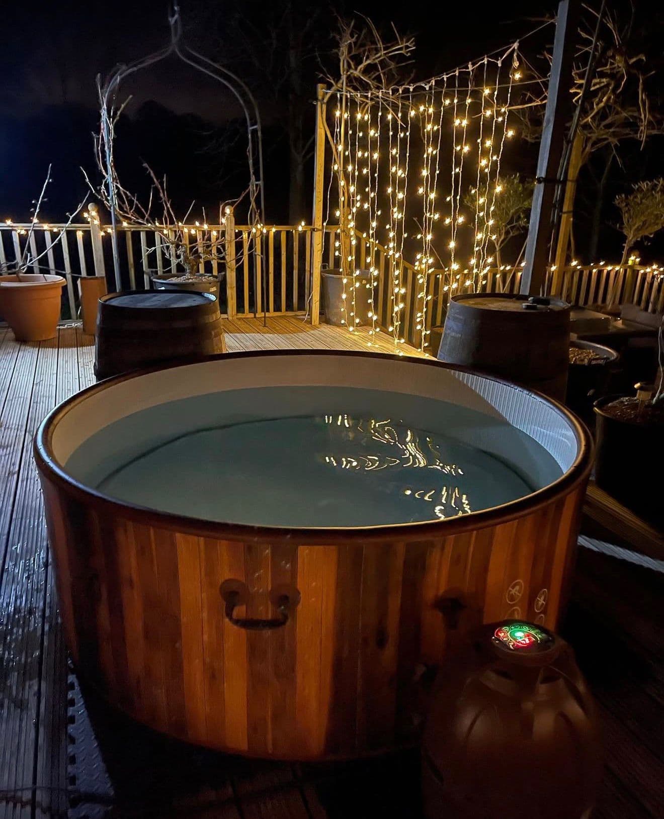 Hot tub set up on home decking at night with fairy lights